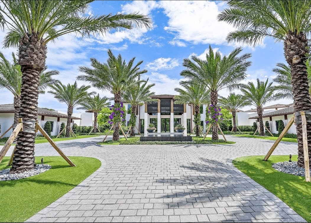 Grand mansion entrance framed by tall palm trees.