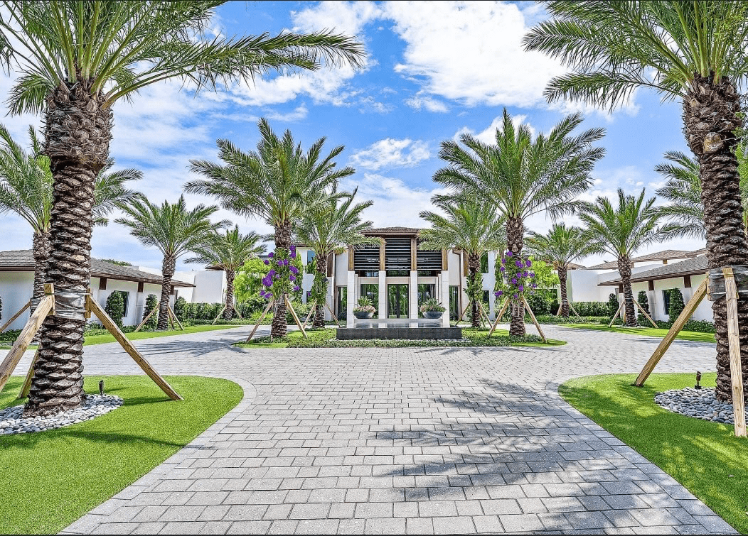 Grand mansion entrance framed by tall palm trees.