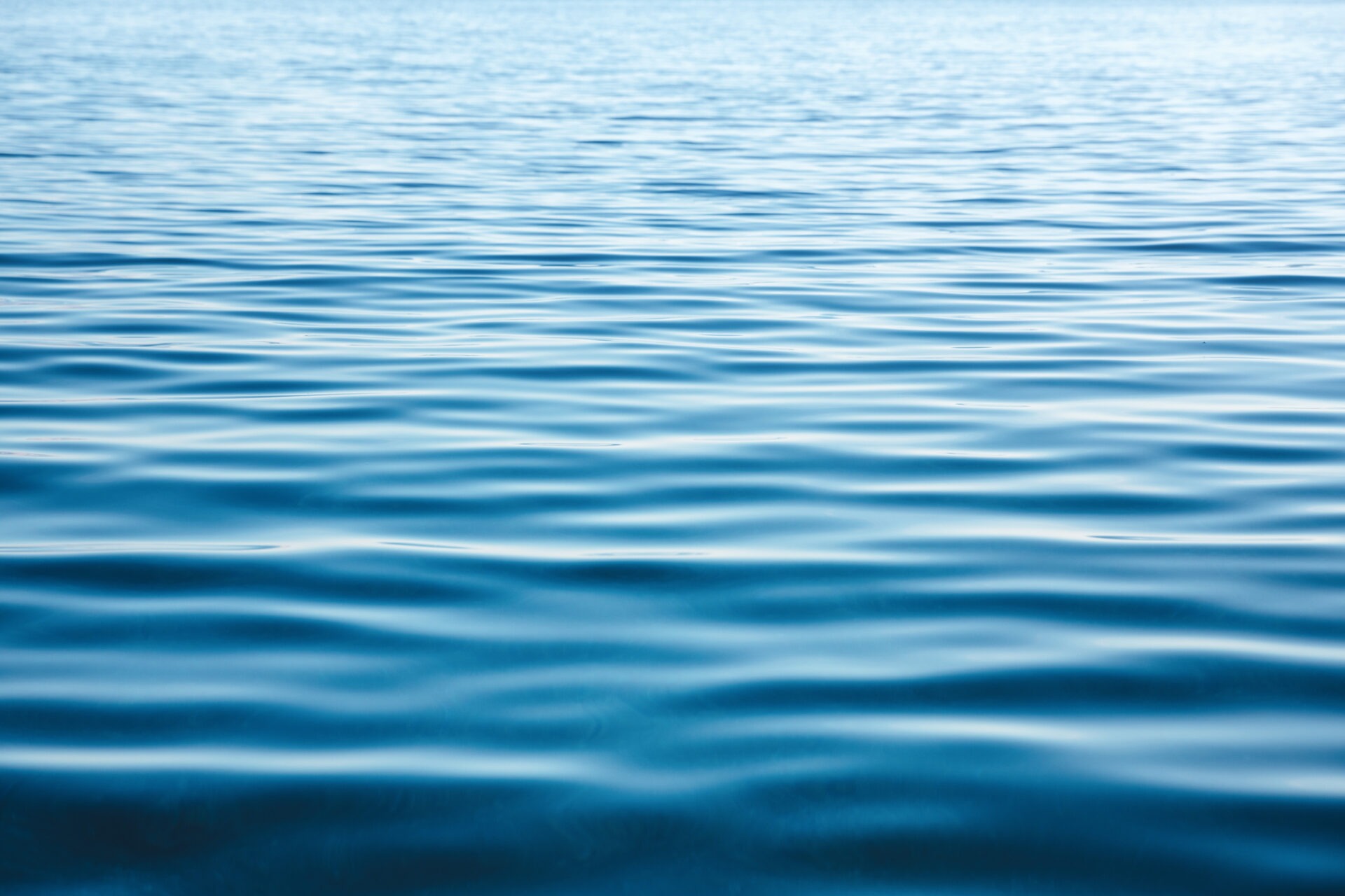 Calm blue water surface with gentle ripples reflecting daylight, creating a peaceful, serene ambiance without any visible landmarks or people present.